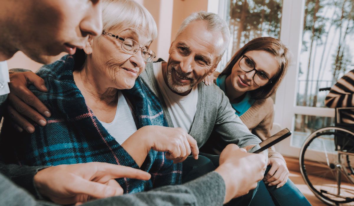 A family sitting close together and smiling with an older relative