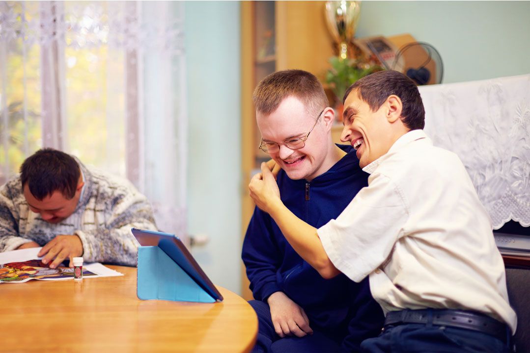 Two men laughing together at a table at home